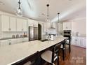 Bright kitchen boasts an oversized island with seating, sleek stainless appliances, and modern lighting at 12508 Asbury Chapel Rd, Huntersville, NC 28078