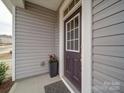 Inviting front door with glass accents, decorative flower pot and neutral colored siding at 15040 Cordelia Dr, Charlotte, NC 28278