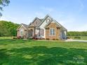 Beautiful home with stone and siding exterior, manicured lawn, and mature trees at 16160 Hopewell Church Rd, Midland, NC 28107