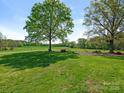 Expansive lawn with mature trees and a tranquil seating area at 16160 Hopewell Church Rd, Midland, NC 28107