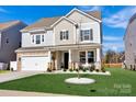 Charming two-story home featuring stone accents, a covered porch, manicured lawn and a two car garage at 187 Tetcott St, Mooresville, NC 28115
