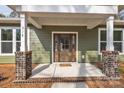 Close-up of a beautiful stained wood front door with glass panels, framed by brick columns and white trim at 318 Lewis Ferry Rd, Statesville, NC 28677