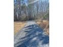 A freshly graveled driveway lined with mature trees leading to the property at 37254 Barnhardt Rd, New London, NC 28127
