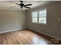 A well-lit bedroom featuring hardwood flooring, ceiling fan, and a bright window at 4825 Farm Pond Ln, Charlotte, NC 28212