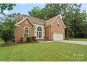 Charming brick home featuring an attached two-car garage and well-manicured lawn at 8731 Sheltonham Way, Charlotte, NC 28216