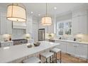 Bright kitchen with white cabinets, quartz countertops, stainless steel appliances, and a large center island with seating at 116 S Broad St, Waxhaw, NC 28173