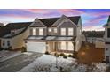 A beautiful two-story home featuring a gray exterior, stone accents, and a well-lit front yard at dusk at 163 W Heart Pine Ln # 51, Statesville, NC 28677