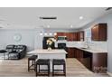 Stylish kitchen with wooden cabinets, granite counters, island with stools, and sleek black appliances at 2462 Willow Pond Se Ln, Concord, NC 28025