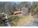 Expansive view of a brick home with a large yard and detached garage nestled in a wooded setting at 10007 Mountain Apple Dr, Mint Hill, NC 28227
