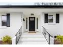 Inviting front porch with black door, white painted brick, and black railings on a sunny day at 1121 S Edgemont Ave, Gastonia, NC 28054
