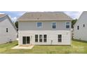 The rear of the home features large windows and sliding glass doors that lead to a patio and grassy backyard at 122 Asmodean Ln, Troutman, NC 28166