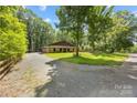 Gravel driveway leading to a charming home surrounded by mature trees at 13124 Lemmond Dr, Matthews, NC 28105