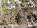 An overhead view captures expansive wooded land nestled amidst elegant homes, accented with private pools and verdant lawns at 8328 Victoria Lake Dr, Waxhaw, NC 28173
