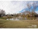 Scenic view of community pond with fountain, surrounded by trees and lush lawns and a blue sky with wispy clouds at 9423 Belmont Ln, Marvin, NC 28173