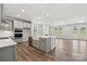 Bright, open kitchen featuring an island, white cabinets, and stainless steel appliances open to the living area at 9932 Manor Vista Trl, Kannapolis, NC 28027