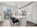 Bright kitchen features an island with seating, stainless steel appliances, and a sliding glass door to the balcony at 2132 Electric Ln, Charlotte, NC 28205