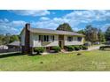 Well-kept home with green lawn, brick chimney, and lush surrounding trees at 3808 22Nd Street Ne Ct, Hickory, NC 28601