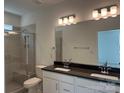 Modern bathroom with double vanity, granite countertop, and a sleek glass-enclosed shower at 407 Sunharvest Ln, Indian Trail, NC 28079