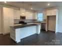 Bright kitchen featuring white cabinets, a large island, stainless steel appliances, and dark hardwood floors at 407 Sunharvest Ln, Indian Trail, NC 28079