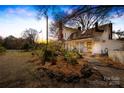 Side view of a charming white two-story home, featuring a front porch and beautifully landscaped yard at 4928 Tuckaseegee Rd, Charlotte, NC 28208