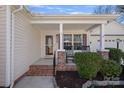 Inviting front porch with rocking chairs, brick accents, and a well-manicured garden at 8408 Williamsburg Cir, Huntersville, NC 28078