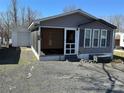 Cozy home with gray siding, a screened porch, an adjacent garage, and a gravel driveway at 134 Cardinal Ave, New London, NC 28127