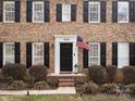 Close-up of the front door with American flag, brick facade, and manicured landscaping with trimmed hedges at 14723 Sapphire Ln, Pineville, NC 28134