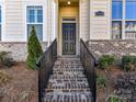 Inviting front entrance with brick steps and wrought iron railing to the black front door at 15140 Rocky Bluff Loop, Davidson, NC 28036