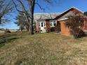Rear exterior view of a brick home with a well-manicured lawn and a peaceful, rural setting at 3423 Crowder Ridge Rd, Shelby, NC 28150