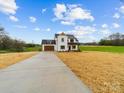 An angle view of a charming two-story modern farmhouse with a long driveway and a sprawling lawn at 1300 Austin Chaney Rd, Wingate, NC 28174