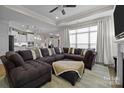 Spacious living room with a large sectional sofa, ottoman, and a view into the open kitchen at 6015 Pleasant Run Dr, Matthews, NC 28104