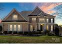 Charming two-story brick home with a lush green lawn and manicured landscaping at sunset at 9433 Wallace Pond Dr, Huntersville, NC 28078