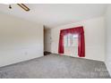 Bright living room with neutral carpet and a window with red curtains at 1022 Kannapolis Pkwy, Concord, NC 28027