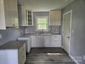 Well-lit kitchen featuring white cabinetry, modern countertops, decorative backsplash, and woodgrain flooring at 126 Lowry St, Chester, SC 29706