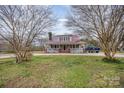 Charming home featuring a classic red roof, inviting front porch and mature trees creating a picturesque setting at 1386 Jennings Rd, Statesville, NC 28625
