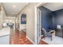 Bright hallway with hardwood floors leads to a cozy sitting area and an office with French doors at 15131 Oleander Dr, Charlotte, NC 28278