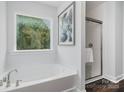 Bright bathroom featuring a soaking tub, glass shower, and a large window for natural light at 1809 Country Club Rd, Lincolnton, NC 10757
