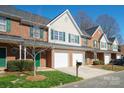 View of brick townhomes with garages, green shutters, and manicured lawns on a sunny day at 2021 Lennox Square Rd, Charlotte, NC 28210