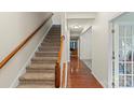 Bright foyer featuring a carpeted staircase with wooden banister, hardwood floors, and abundant natural light at 2177 Galloway Sw Ln, Concord, NC 28025