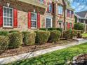 Well maintained lawn with trimmed bushes and red shutters on a two-story brick home at 2907 Blackburn Dr, Waxhaw, NC 28173