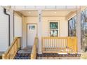 Up close view of a charming covered front porch with wood railings and a brick foundation at 427 Queens Ct, Gastonia, NC 28052