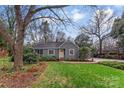 Inviting single-story home showcasing lush landscaping, a yellow front door, and a cozy screened-in porch at 1416 Woodland Dr, Charlotte, NC 28205