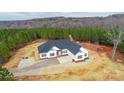 An aerial view of a single-story home featuring white siding, dark shutters, and a red front door amid a lush landscape at 150 Belk Estate Dr, Mooresville, NC 28115