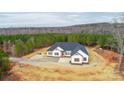 This aerial showcases a white single-story home with a red door, nestled in a serene, tree-lined landscape at 150 Belk Estate Dr, Mooresville, NC 28115