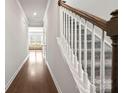 Hallway featuring hardwood floors leading to a carpeted staircase and a sunlit living area at 2131 Belterra Dr, Charlotte, NC 28216