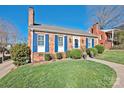 Charming brick home featuring a blue door, shutters, and a well-manicured front yard at 228 Wales Ave, Charlotte, NC 28209