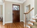 Grand entryway featuring hardwood floors, staircase with white railings, and wooden front door at 261 Crownsgate Ct, Charlotte, NC 28207