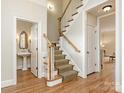Hallway with wooden floors, staircase with runner, and access to a powder room and other rooms at 261 Crownsgate Ct, Charlotte, NC 28207