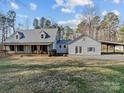 Back of the home, featuring a metal roof, a large building with a garage, and natural surroundings at 265 River Run Rd, Statesville, NC 28625