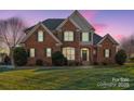 Charming two-story brick home with meticulously manicured lawn and mature landscaping at twilight at 8018 Cotton St, Harrisburg, NC 28075